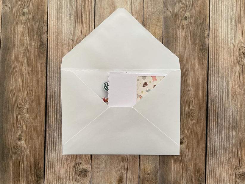 White envelope with a floral card on a wooden surface