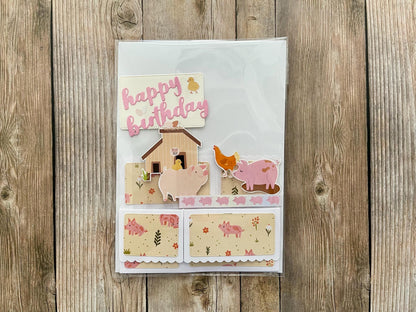 Children's birthday card with farm animal illustrations on a wooden surface