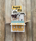 Folding card with farm-themed illustrations on a wooden background
