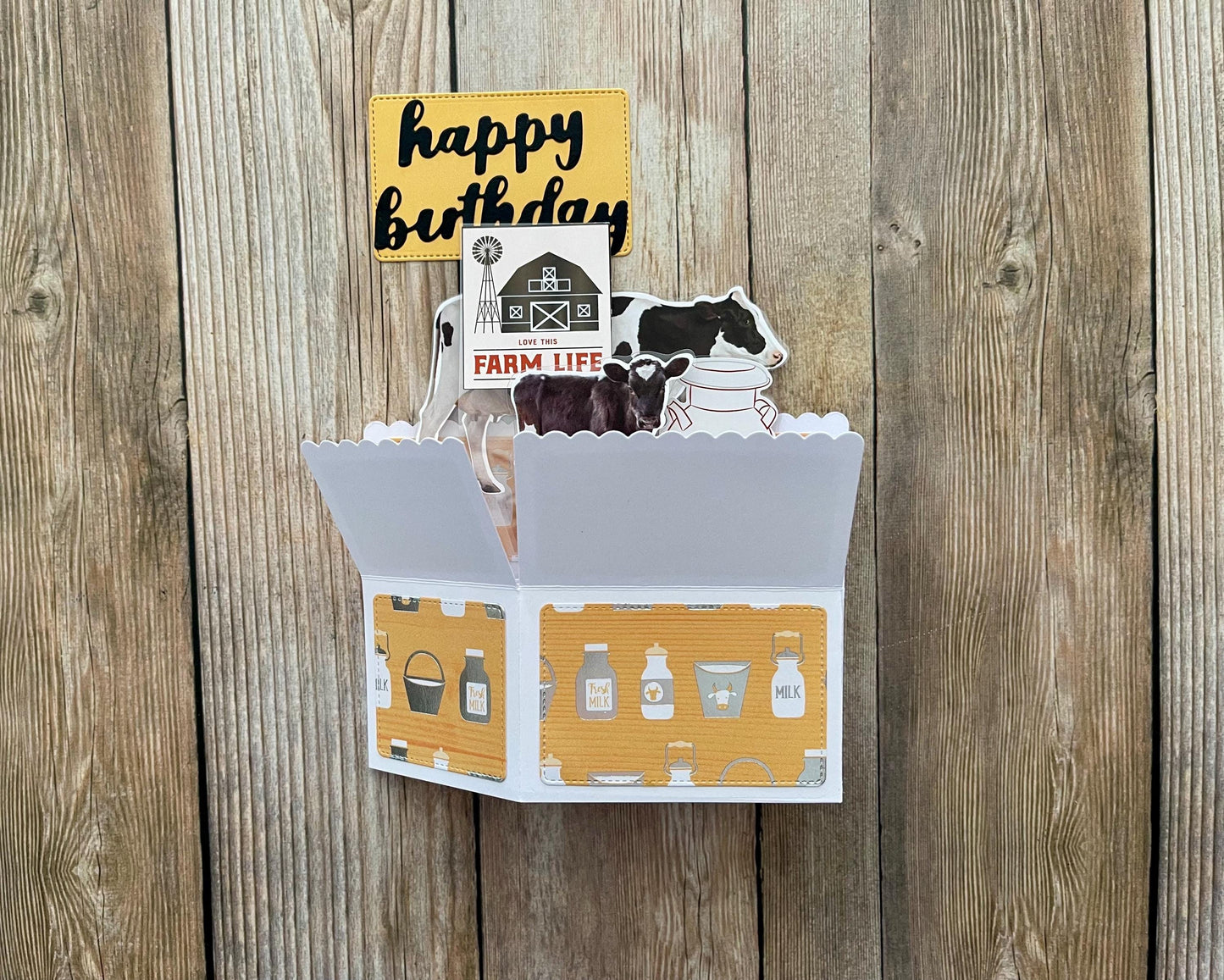 Card with farm-themed illustrations and 'happy birthday' sign on a wooden background