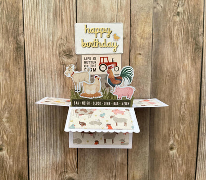 Pop-up birthday card with farm animal illustrations on a wooden background