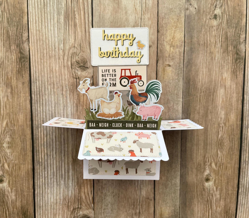 Pop-up birthday card with farm animal illustrations on a wooden background