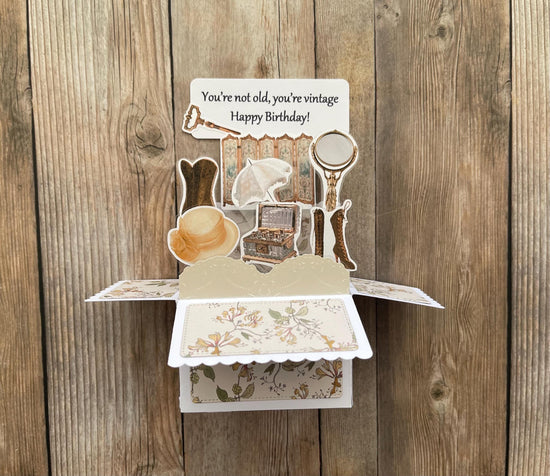 Vintage-themed birthday card with pop-up elements on a wooden background