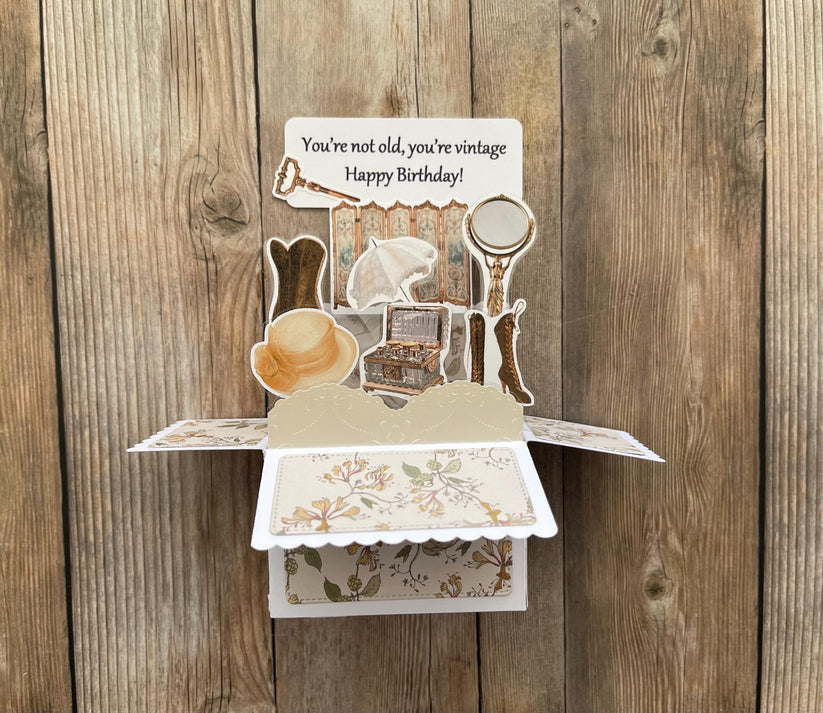 Vintage-themed birthday card with pop-up elements on a wooden background