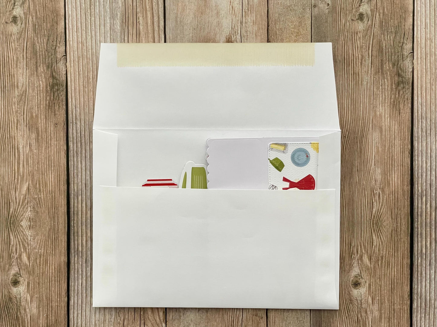 White envelope with a colorful card on a wooden surface