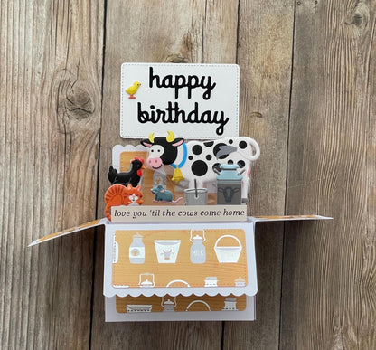 Pop-up birthday card with farm-themed illustrations on a wooden background