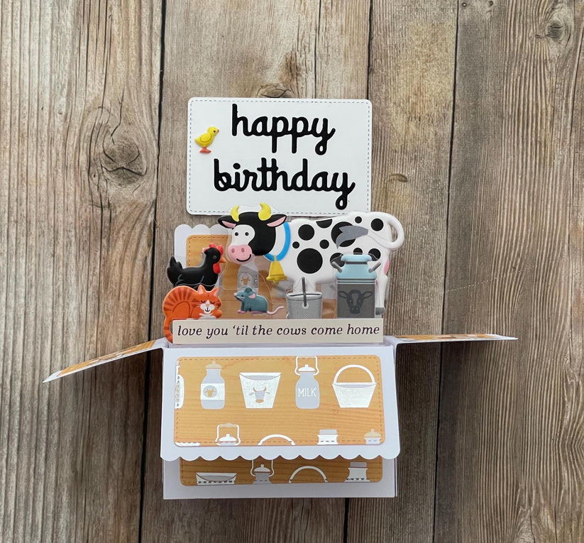 Pop-up birthday card with farm-themed illustrations on a wooden background